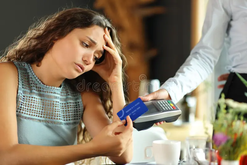 cliente preocupado pagando conta cara em um restaurante com cartão de crédito 259705882